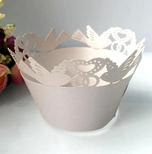 Detailed laser-cut cupcake wrapper featuring heart and bird patterns for wedding decor