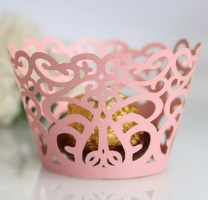 Close-up of pink laser-cut cupcake wrappers with intricate vine filigree and wavy edges