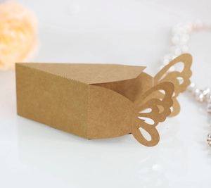 Detail of kraft paper favor box with laser-cut butterfly closure and wedding decor