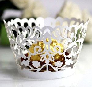 Macro view of white laser-cut cupcake wrapper with floral lace patterns and scalloped edge