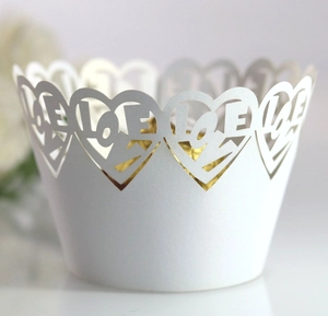 Macro shot of white laser-cut cake wrapper featuring heart shapes and LOVE lettering