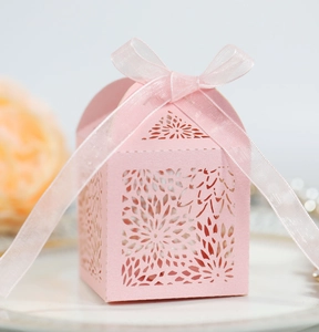Pink laser-cut wedding favor box with floral patterns and a matching organza ribbon bow