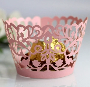 Pink laser-cut lace cupcake wrappers with intricate vine design for party decorations