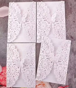 Detailed laser-cut white wedding invitations with intricate floral and butterfly designs