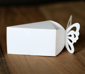 Macro view of white butterfly laser cut wedding favor box on dark wood surface