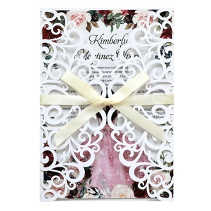 Détail de l'invitation de mariage blanche découpée au laser avec ruban et motif floral