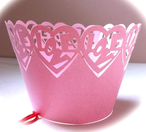 Close-up of pink laser-cut cupcake wrapper with artistic heart and LOVE patterns