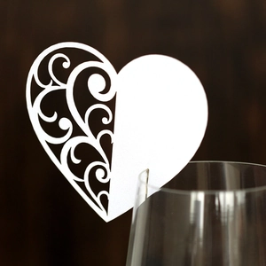 Macro detail of white heart wine glass place card with laser-cut lace pattern for weddings