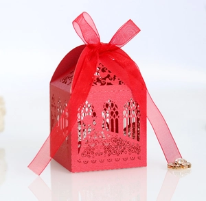Détail d'une boîte à bonbons de mariage découpée au laser avec motifs floraux et ruban rouge