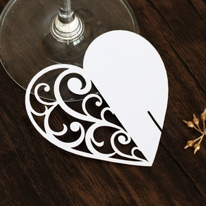 Macro shot of white heart laser-cut card for wedding wine glass seating decoration