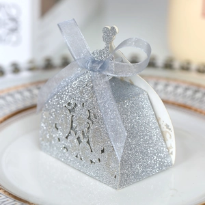 Close-up of a silver glitter wedding favor box shaped like a dress with a satin bow