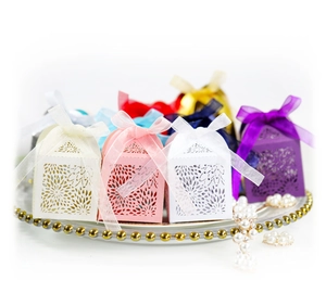 Elegant laser-cut wedding favor boxes in various colors with ribbon bows and floral patterns
