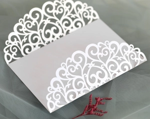 Détail d'invitation de mariage découpée au laser blanc avec motifs de volutes complexes