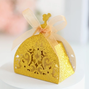 Detail of golden glitter princess dress favor box with hollow pattern and ribbon