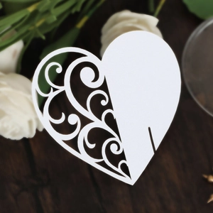 Detailed macro view of laser-cut heart place cards with intricate vine patterns on white cardstock