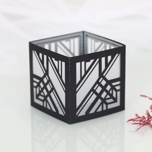 Macro detail of laser-cut geometric paper candle shade in matte black for party decor