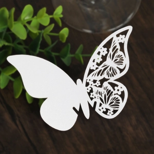 Detailed view of laser-cut white butterfly place card with intricate floral patterns