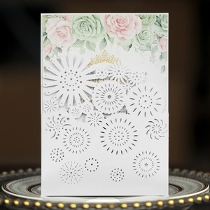 Laser-cut white wedding invitation featuring floral patterns and gold crown detailing