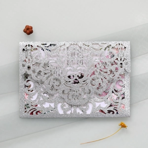 Detail of silver glitter laser-cut invitation with floral card on grey textured background