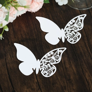Detailed close-up of white butterfly place cards with intricate laser-cut floral patterns
