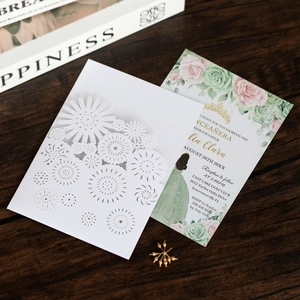 Detail of laser-cut wedding invitation with floral insert on dark wooden background