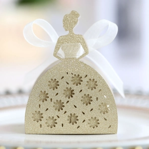 Detailed close-up of golden glitter laser-cut dress favor box with white organza ribbon bow