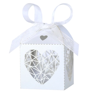 Détails de motifs de cœurs évidés sur boîte à bonbons de mariage ivoire avec ruban blanc