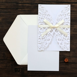 Détail de découpe laser sur invitation blanche avec un élégant nœud en ruban beige