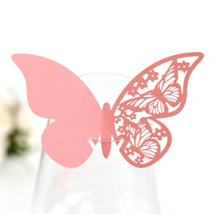 Detail of pink laser-cut butterfly place card with floral hollow pattern on a wine glass