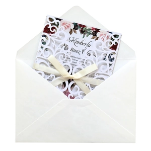 Détail de l'invitation de mariage découpée au laser avec nœud en soie et motif floral