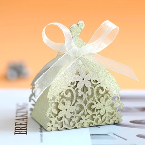 Close-up of golden glitter laser-cut dress favor box with a white organza ribbon bow