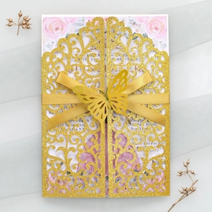 Détail d'une invitation de mariage dorée pailletée avec découpe laser papillon et décor floral