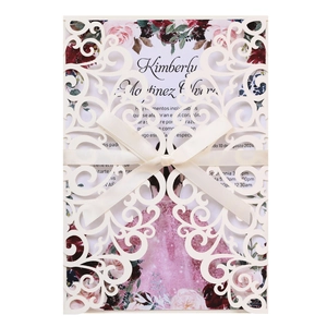 Détail d'invitation de mariage découpée au laser avec motifs floraux et nœud en satin