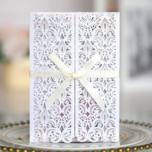 Détail d'invitation de mariage découpée au laser avec un élégant ruban de soie beige