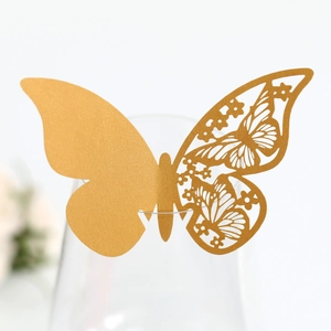 Close-up of golden 3D laser-cut butterfly place card on a crystal glass rim
