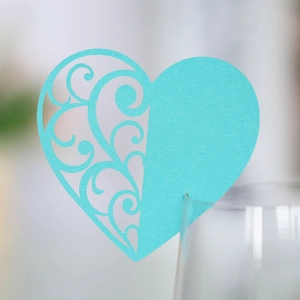 Close-up of sky blue heart-shaped laser-cut place card with elegant vine patterns