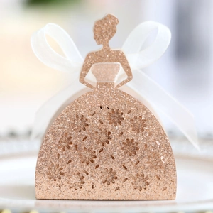 Detail of laser-cut bridal dress favor box with champagne gold glitter and organza bow