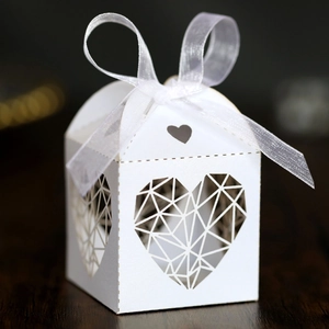 Détail de la boîte à bonbons ivoire avec motif de cœur découpé au laser et ruban blanc