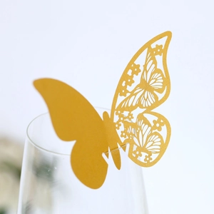 Macro shot of gold laser-cut butterfly place card with floral hollow pattern on glass