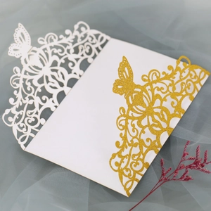 Macro view of laser-cut glitter paper wedding invitation with butterfly and scroll patterns