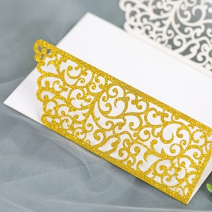 Gros plan d'une invitation de mariage dorée pailletée avec motif floral découpé au laser