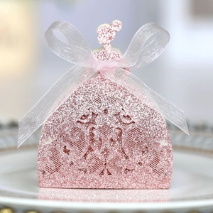 Close-up of pink glitter dress-shaped party favor box with white ribbon and cutout pattern