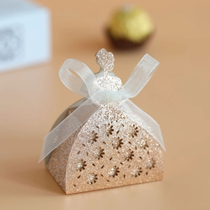 Close-up of laser-cut wedding favor box in bridal gown shape with champagne gold glitter