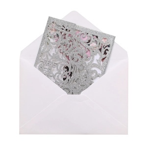 Detailed silver glitter laser-cut wedding invitation cover with a matching white envelope