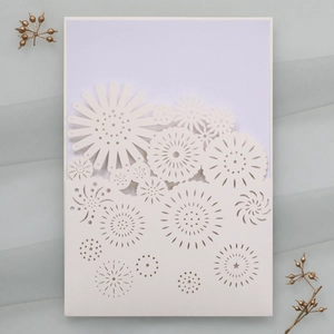 Detailed laser-cut floral pattern on a white wedding invitation with elegant hollow design
