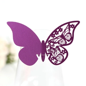 Detail of purple laser-cut butterfly place card with floral patterns on glass rim