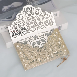 Detail of laser-cut glitter wedding invitation with intricate floral hollow patterns