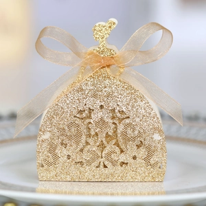 Close-up of golden glitter laser-cut dress-shaped favor box with an organza ribbon bow