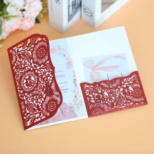 Detail of red glitter card with laser-cut Fu character and floral wedding invitation