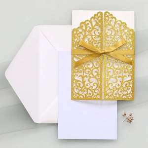 Détail d'invitation de mariage dorée découpée au laser avec ruban en satin chic